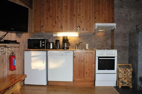 una cocina con electrodomésticos blancos y armarios de madera en Mäntyrinne, en Syöte