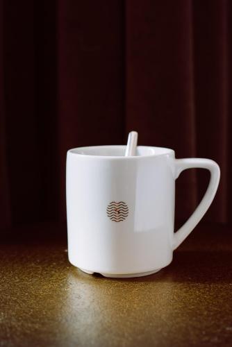 a white coffee cup with a straw in it at Boutique Hotel Sablon by CW Hotel Collection in Bruges