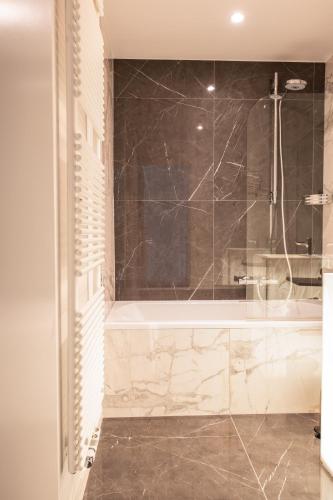 a bathroom with a tub and a shower with a glass door at Boutique Hotel Sablon by CW Hotel Collection in Bruges