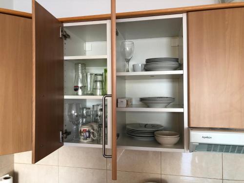 a kitchen cabinet with plates and dishes in it at APT with terrace facing Amadores beach in Amadores