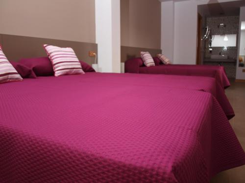 a large pink bed with purple sheets and pillows at Hostal La Ribera del Júcar in Cuenca