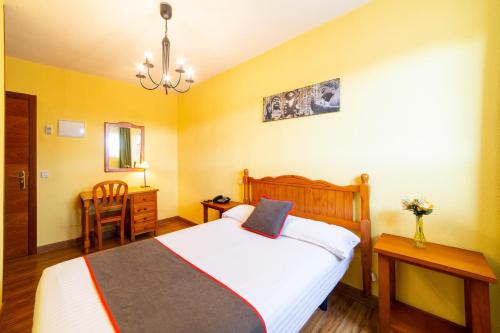 a bedroom with a bed and a table and a chair at Hotel Mavi in La Cabrera