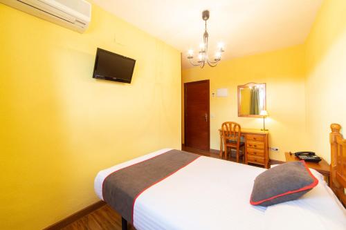 a bedroom with a bed and a tv on the wall at Hotel Mavi in La Cabrera