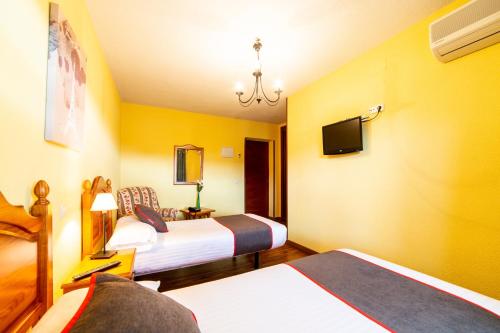 a hotel room with two beds and a tv at Hotel Mavi in La Cabrera