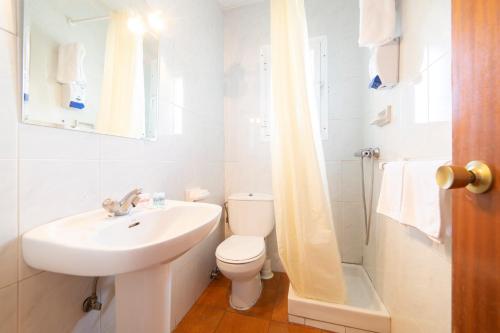 a white bathroom with a sink and a toilet at Hotel Mavi in La Cabrera
