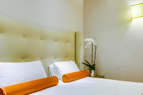 a bedroom with a bed with white sheets and orange accents at Solo Experience Hotel in Florence