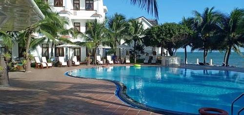 a large swimming pool next to a building and the ocean at Muine Pacific Resort in Mui Ne