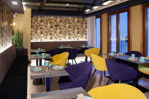un restaurante con mesas y sillas de color púrpura y amarillo en Palacete Colonial, en León