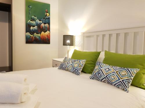 um quarto com uma cama branca e almofadas verdes em Vieira Apartments II em Setúbal