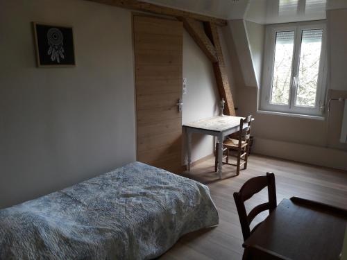 a bedroom with a bed and a table and a window at La Cense Hebron in Ardres