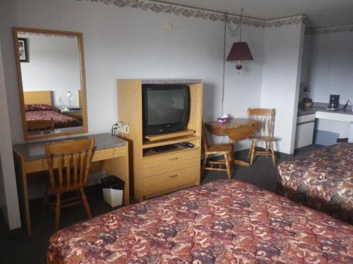 um quarto de hotel com uma televisão, uma cama e uma secretária em Alcan Motor Inn em Haines Junction