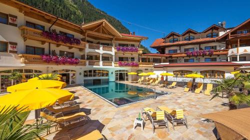 um hotel com piscina, cadeiras e guarda-sóis em Hotel Edenlehen em Mayrhofen