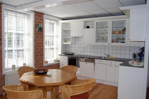 Una cocina con gabinetes blancos y una mesa de madera. en Bed&Brood De StraVerdonk, en Graft