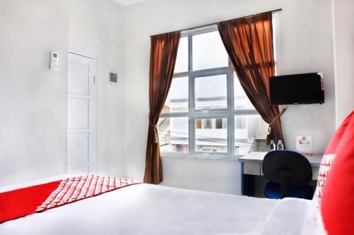 1 dormitorio con cama, escritorio y ventana en OYO 120 GP Residence, en Kampung Sawah