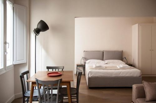 1 dormitorio con 1 cama, mesa y sillas en Pietrapiana Boutique Apartments, en Florencia