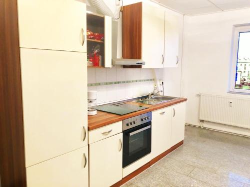 a kitchen with white cabinets and a sink at #WORLD Monteurzimmer in Schkeuditz