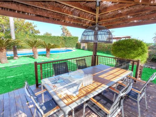 einen Holztisch und Stühle auf einer Terrasse in der Unterkunft Villa Cala Vidre B by Interhome in Les tres Cales