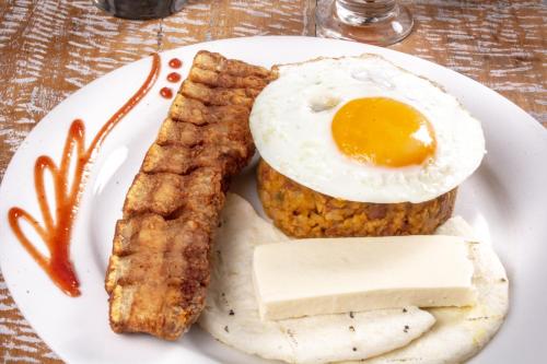 a plate of food with an egg and some meat at Hotel Mediterraneo in Medellín