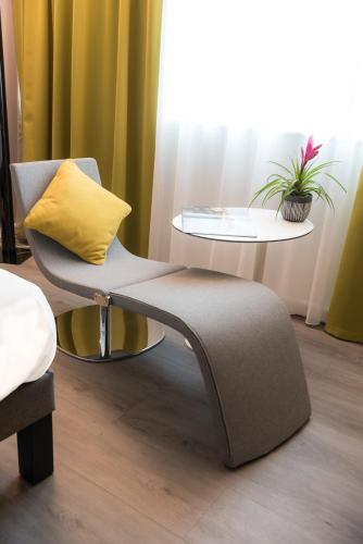 a chair with a yellow pillow sitting next to a table at Novotel Chartres in Chartres