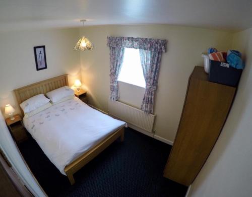 a small bedroom with a bed and a window at Cosy Keel Cottage in Keel