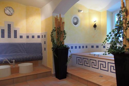 uma casa de banho com 2 lavatórios, uma banheira e um relógio. em Hotel Schlossvilla Derenburg em Derenburg