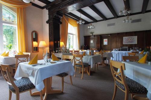 uma sala de jantar com mesas e cadeiras brancas em Hotel Schlossvilla Derenburg em Derenburg
