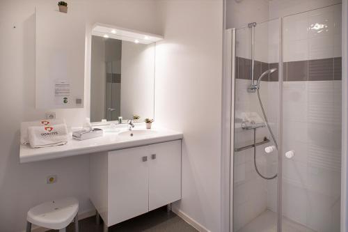 a white bathroom with a sink and a shower at DOMITYS LES SABLES D'OR in Villeneuve-le-Roi