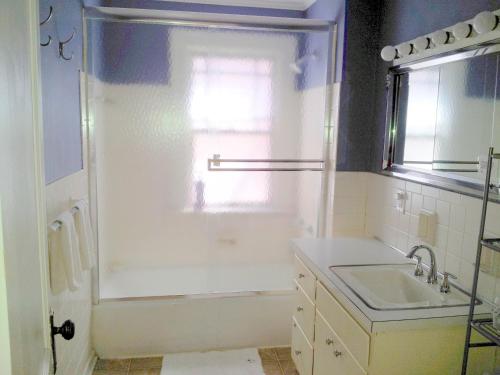 a white bathroom with a sink and a shower at The Wayfaring Buckeye Hostel in Columbus