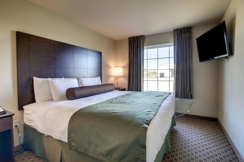 a hotel room with a large bed and a flat screen tv at Cobblestone Inn & Suites - Avoca in Avoca