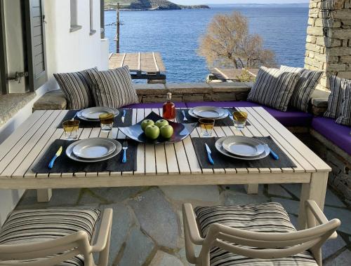 a wooden table with a plate of fruit and wine glasses at Aqua Blue, only 100 meters from the beach of Gialiskari in Ioulida