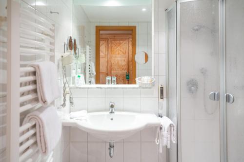 a white bathroom with a sink and a shower at Aktiv Hotel Schweiger in Füssen