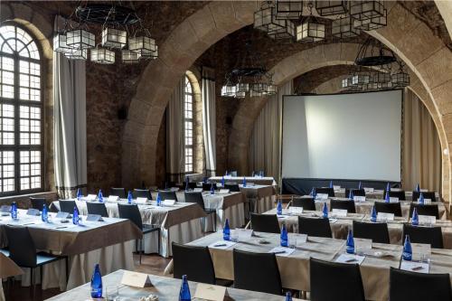 a large room with tables and chairs and a screen at Parador de Siguenza in Sigüenza