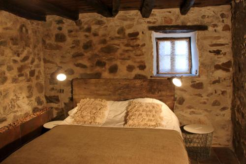 una camera con un letto in una stanza in pietra con finestra di Casa Javali a Chiqueiro