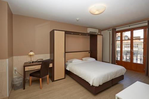 Una habitación de hotel con una cama y un escritorio y un escritorio. en Hotel Central, en Ginebra