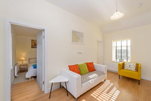 a living room with a white couch and a yellow chair at Garra Cottage in Drogheda