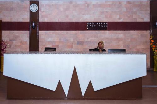 a man sitting at a reception desk in a lobby at Freedom City Hotel Najjanankumbi Kamapala in Kampala