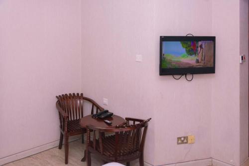 a room with a table and two chairs and a television on a wall at Freedom City Hotel Najjanankumbi Kamapala in Kampala