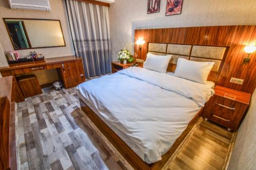 a bedroom with a large white bed and a mirror at MARİNA HOTEL in Izmir