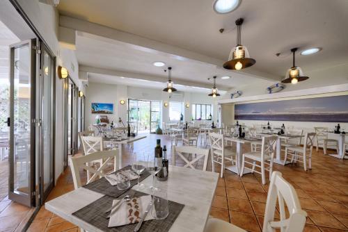 a restaurant with white tables and white chairs at Le Esperidi Camping Ecoresort in Marina di Bibbona