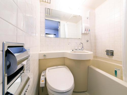 a white toilet sitting next to a sink in a bathroom at APA Hotel Aomorieki-higashi in Aomori