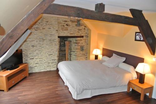 um quarto com uma cama branca e uma parede de tijolos em L 'Annexe em Lohéac