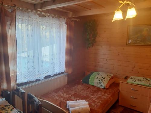 Dormitorio con ventana y cama. en Pokoje u Heleny, en Leśnica