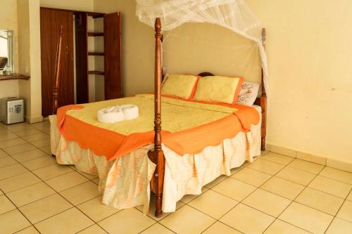 a bedroom with a bed with an orange comforter at Sunrise Apartments Hotel Fort Portal in Fort Portal