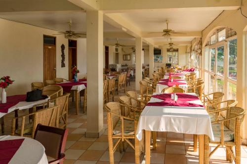 a row of tables in a restaurant with red tablecloths at Sunrise Apartments Hotel Fort Portal in Fort Portal