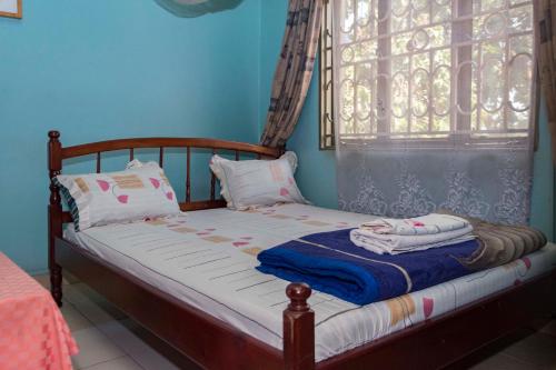 un petit lit dans une chambre avec une fenêtre dans l'établissement Rosama Guest House Najjanankumbi Kampala, à Kampala