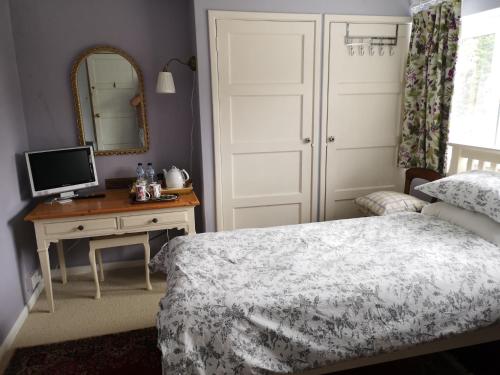 a bedroom with a bed and a desk with a mirror at UPTHEDOWNS B&B in Sevenoaks