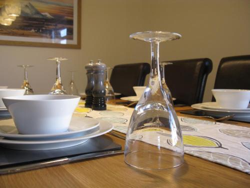 a glass bottle on a table with plates and bowls at Seabreeze Apartment in Keiss