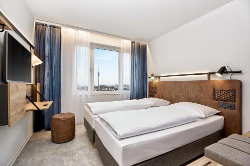 a hotel room with two beds and a window at H2 Hotel München Olympiapark in Munich