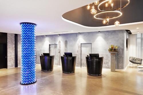 a lobby with a blue pillar and black trash cans at H2 Hotel München Olympiapark in Munich