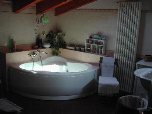 uma grande banheira branca numa casa de banho com lavatório em Il Giuggiolo em Calco